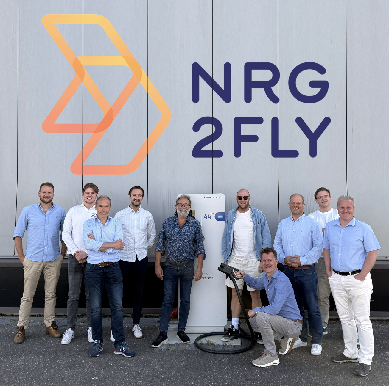 The NRG2fly team in front of the NRG2FLY logo and aircraft charger